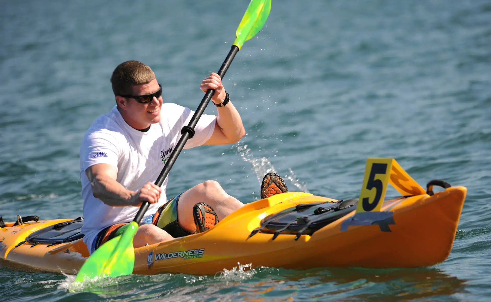 smiling man in white crew neck t shirt wearing sunglasses paddling on yellow kayak during daytime