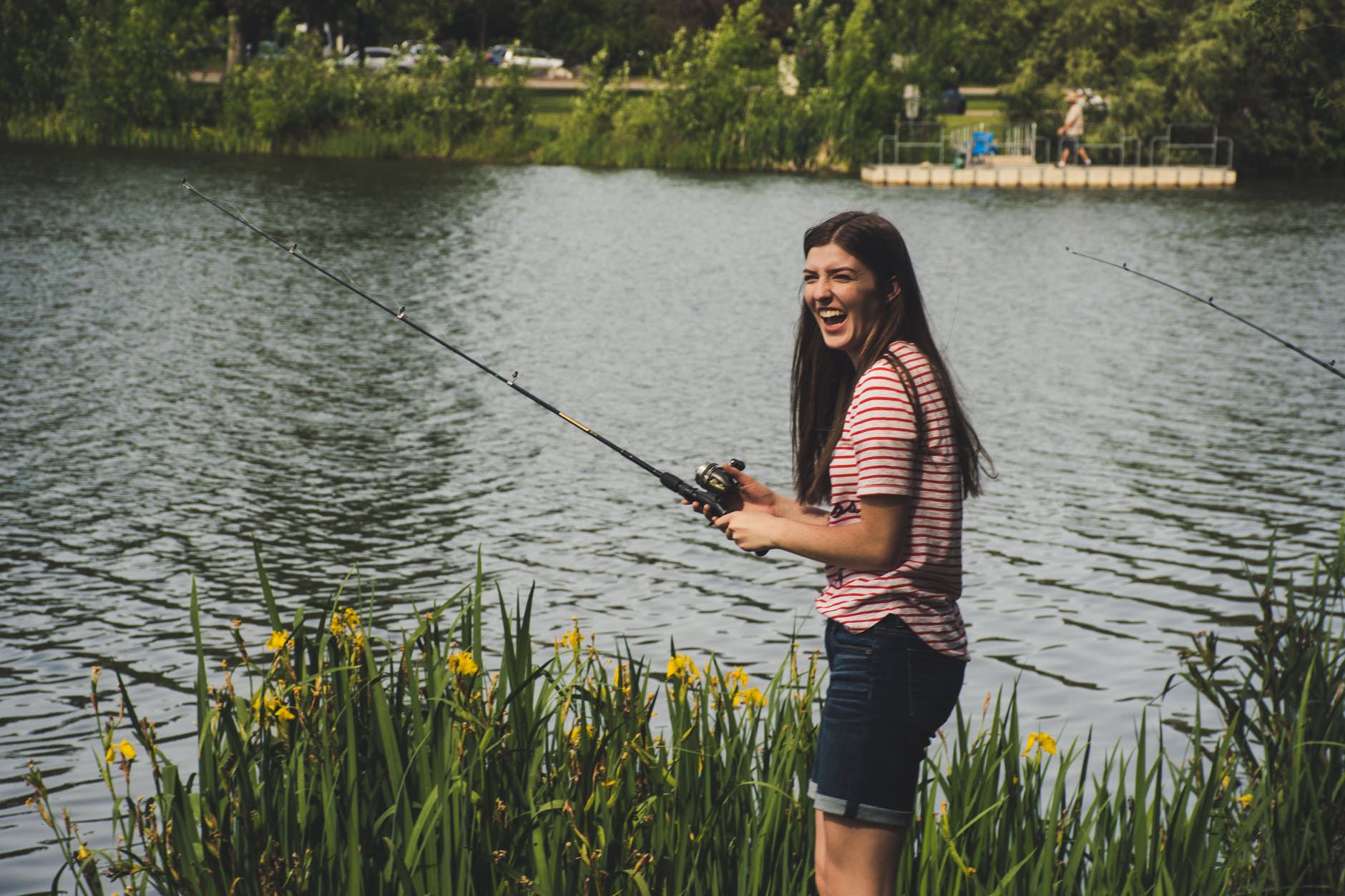 woman in red striped shirt and blue denim shorts holding fishing rod