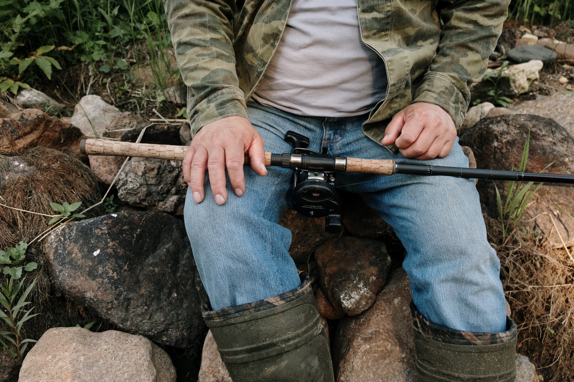 person in green and brown camouflage jacket and blue denim jeans holding black and brown rifle