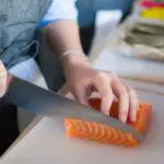 person slicing meat on white chopping board
